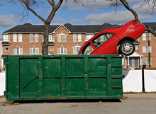 Red Car Thrown In A Green Dumpster