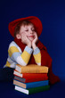Little boy in colorful clothes dreaming on a pile of books