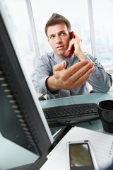 Businessman on call waving working in office