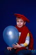 Blond boy in red scarf smiling with blue balloon