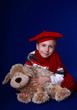Little boy smiling in red scarf and beret with a toy dog