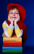Little boy in red beret with colorful books smiling