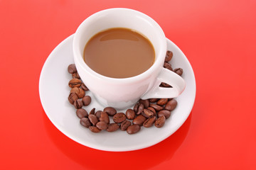 Wall Mural - Small white cup of coffee with coffee grain  on red background