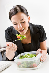 Wall Mural - Businesswoman eating salad at desk