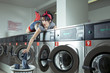 Frau im Waschsalon befüllt eine Waschmaschine