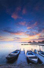 Peaceful Sunrise With Dramatic Sky And Boats And A Jetty