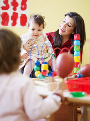 two little girls and female teacher in kindergarten