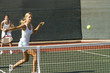 doubles tennis player hitting tennis ball with backhand