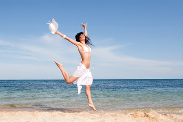 happy young woman jumping in the beach