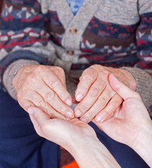 Young doctor holds old man's hands