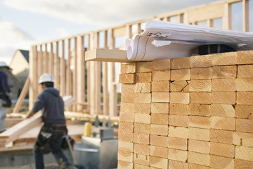 Stacked Lumber and Blueprints at a Construction Site