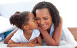 © WavebreakMediaMicro - Cute little girl woman kissing her mother lying down on bed
