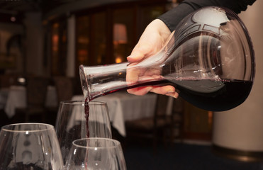 Waiter pouring red wine from decanter