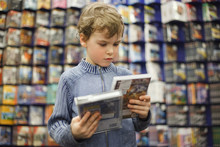 Boy Chooses One Of Two Dvd In Special Store, Ready Contents
