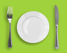 Knife, White Plate And Fork On Green Background