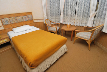 Single bed in modern hotel room with table and chairs