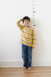 © Todd Wright/Blend Images - Asian boy standing next to height markers on wall