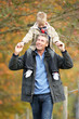 © micromonkey - Man With Young Son On Shoulders Autumn Park