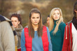 Teenage Girl Surrounded By Friends In Outdoor Autumn Landscape
