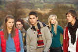Fototapeta Londyn - Teenage Boy Surrounded By Friends In Outdoor Autumn Landscape