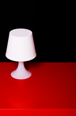 Detail of a white lamp on a red table, isolated on black backgro