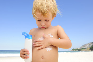 cute child applying  sunscreen  at the beach