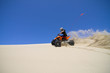 Large sand spray from ATV quadbike rider in the dunes