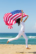 © michaeljung - young woman holding american flag on  beach