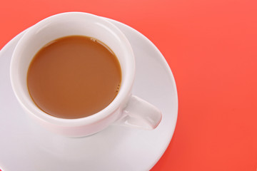 Wall Mural - Small white cup with coffee on red background