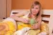 Bautiful young woman on a bed and drinking cofee