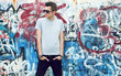 © originalpunkt - young man posing in front of a colorful graffiti wall