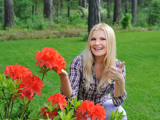 Beautiful gardener woman with red flower bush outdoors