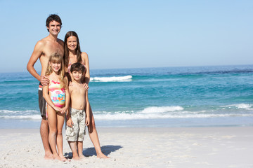 Young Family Standing On Sandy Beach on Holiday