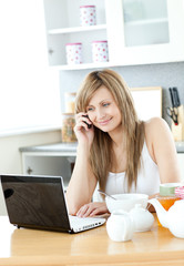 Canvas Print - Delighted woman using a laptop in the kitchen