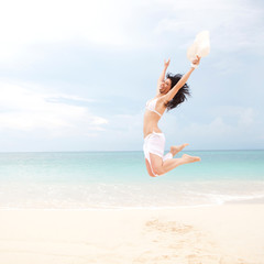 Wall Mural - happy young woman jumping in the beach