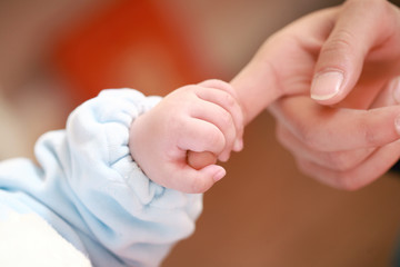 a baby holding his mother's big finger