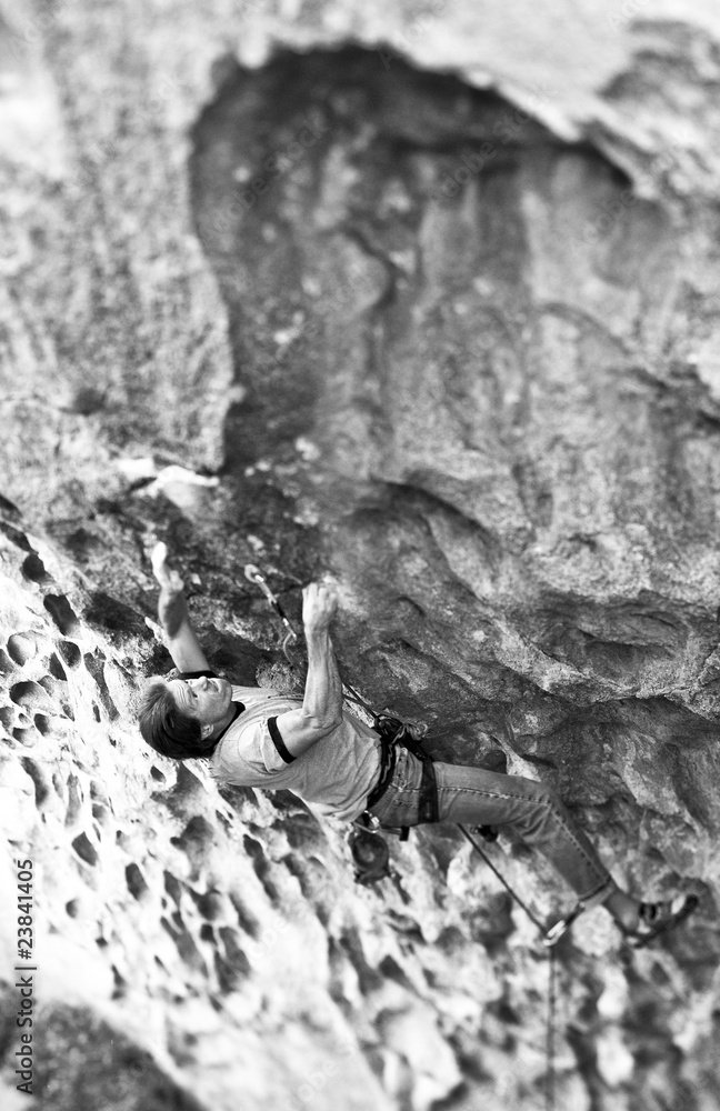Rock climber clinging to steep cliff. - obrazy, fototapety, plakaty 