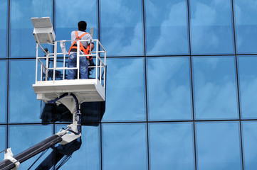 Window washing on high-rise office building in crane beam