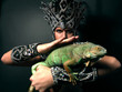 Young pagan priest in ritual suit with green iguana in his hands