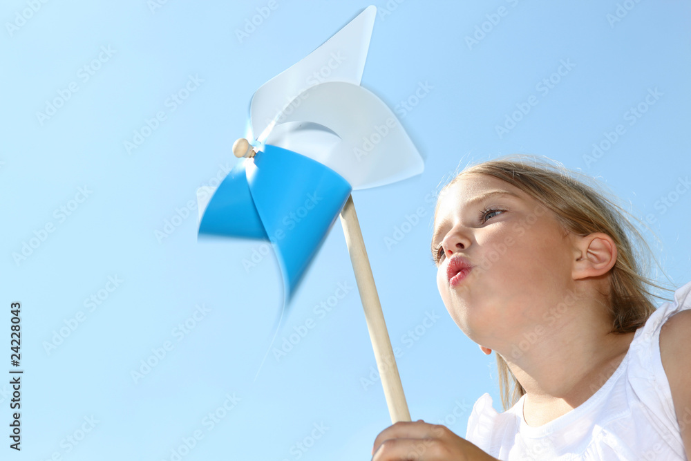 Closeup of little girl blowing blue wind wheel - obrazy, fototapety, plakaty 