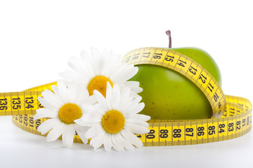 Green apple, flowers and measuring tape.