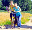 © gb - Beautiful smiling girls walk with bicycle on village road