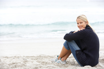 Wall Mural - Young Woman On Holiday Sitting On Winter Beach