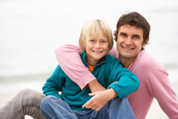 Wall Mural - Father And Son Sitting On Winter Beach Together