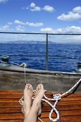 Wall Mural - man feet relax on golden wooden old sailboat