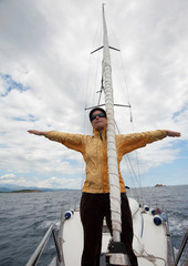 Wall Mural - Young woman in yellow jacket having fun on the front of a yacht