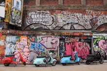 Four Mopeds In Front Of Graffiti