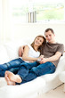 © WavebreakMediaMicro - Attentive young couple watching television lying on the sofa