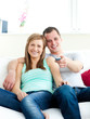 © WavebreakMediaMicro - Glowing young couple sitting on the sofa watching tv