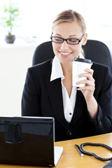 Poster - Positive caucasian businesswoman holding a coffee using her lapt